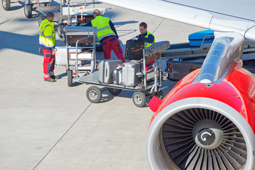 Flughafenmitarbeiter verladen Koffer aus Flugzeug